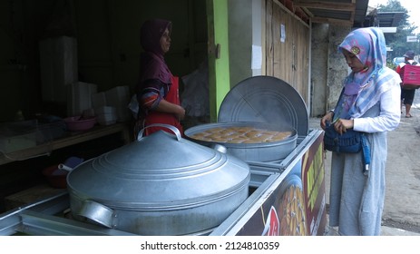 Bandung, Indonesia - Feb 02 2022 : Woman selling Apang Coe on street stall. It is steamed individual cake from Manado, Sulawesi, Indonesia made of rice flour and palm sugar, served with grated coconut