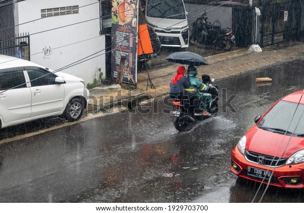 Bandung, Indonesia - February 4, 2021:\
Riding a motorcycle in the rain and use\
umbrellas.