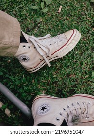 Bandung Indonesia, July 19, 2022: White Converse Shoes On Green Field. White Sneakers On Green Field Background With Copy Space. Top View.