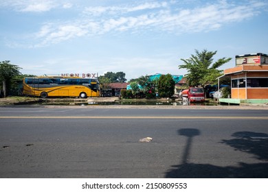 Bandung, Indonesia - March 24, 2022: Yellow Commercial Bus, Red Truck In The Pool And Blue Sky. 