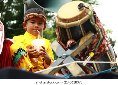 BANDUNG, INDONESIA - November 06, 2012 :a small child who is following a carnival on the street wearing a traditional costume, is drinking because he is thirsty
