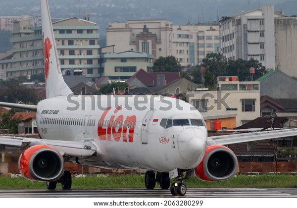 Bandung, October 2021: A lion air\
plane is seen parked in a circle with buildings and housing in the\
background at Husein Sastranegara International\
Airport.