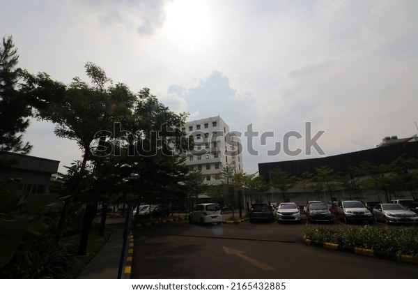 Bandung, West Java, Indonesia - January 10,\
2022: Landscape view of an Outdoor parking lot with trees and cars\
parked in an outdoor Shopping center parking lot in Bandung, West\
Java, Indonesia.