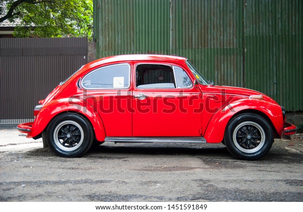 Bandung, West\
Java / Indonesia - November 29th 2013: A classic, red Volkswagen\
Beetle parking in the\
street.