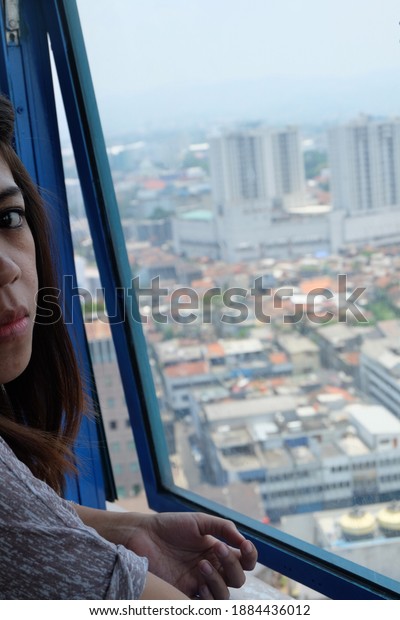 Bandung, West Java,\
Indonesia, Oktober 15, 2013. A woman looks at the city view from\
the top of the tower