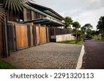 Bandung, west java, March 24,2023 - Minimalist House Design, Brown metal profile fence, entrance with main gate, metal gate with vertical lines. Outside there are palm trees. 