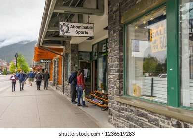 BANFF, AB, CANADA - JUNE 2018: People Walking Along A Row Of Shops In Banff Town Centre.