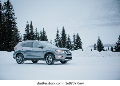 Banff, Alberta / Canada- December 14, 2018: Grey Nissan Rogue parked amidst snowy winter scene. Side view