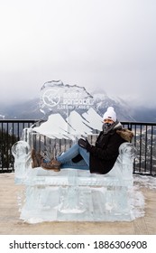 Banff, Canada - December 2020 : Woman Sitting On An Ice Sculpture At The Summit Of Sulphur Mountain