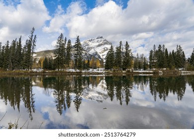 Banff National Park beautiful natural scenery. Cascade Mountain with blue sky, white clouds reflected on Bow River like a mirror in a snowy autumn sunny day. Town of Banff, Canadian Rockies. - Powered by Shutterstock