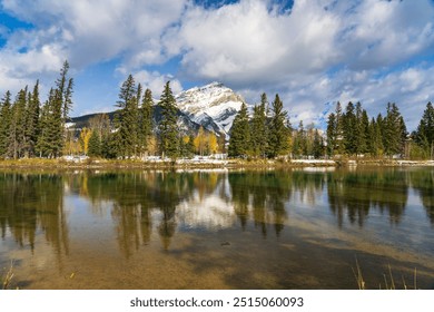 Banff National Park beautiful natural scenery. Cascade Mountain with blue sky, white clouds reflected on Bow River like a mirror in a snowy autumn sunny day. Town of Banff, Canadian Rockies. - Powered by Shutterstock