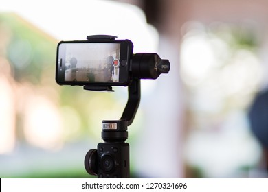 Bang Pa-in, Ayutthaya, Thailand - DEC 21 2018 : Mobile Phone Iphone 8 Is Shooting A Video Using Gimbal Zhiyun Smooth 4 Background Is Bokeh In The Morning Video  Filming Concept