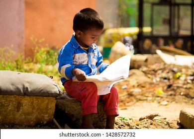 Bangalore, India - February 26, 2019: poor child reading a book in a indian street | supporting education
