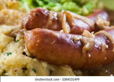 Bangers And Mash. Baked Sausage In Onion Gravy Served With Mashed Potatoes And Cabbage