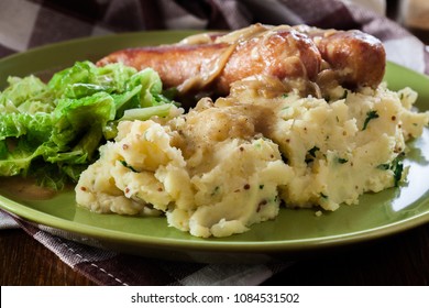 Bangers And Mash. Baked Sausage In Onion Gravy Served With Mashed Potatoes And Cabbage