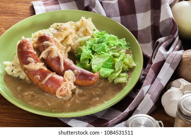 Bangers And Mash. Baked Sausage In Onion Gravy Served With Mashed Potatoes And Cabbage