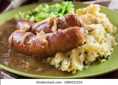 Bangers And Mash. Baked Sausage In Onion Gravy Served With Mashed Potatoes And Cabbage