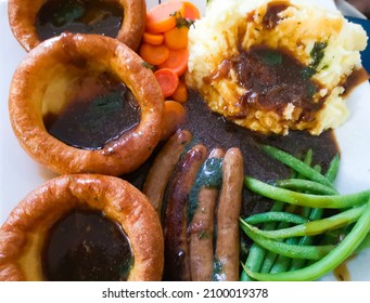 Bangers and mash with mashed potato, Yorkshire puddings and vegetables.