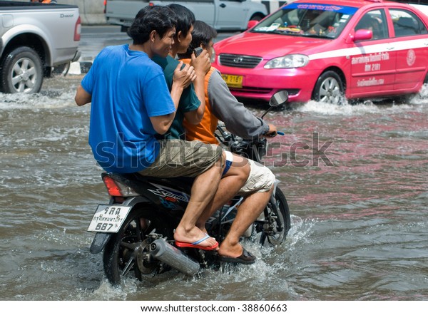 BANGKOK - AUGUST\
14: Three men on a motorbike navigating through the flood after the\
heaviest monsoon rain in 20 years in the capital on August 14, 2009\
in Bangkok, Thailand.