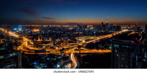 Bangkok City With Curved Express Way And Skyscraper. Top View Of City Elevated Highway With Car Traffic Light Trial At Night Time