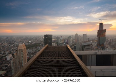 Bangkok city sunset view from rooftop of skyscraper building with steel grate floor 