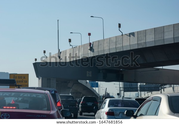 BANGKOK - Jan. 28, 2020: Cars jam on a toll way\
during rush hours usually seen in big cities in a morning. View\
from a front car seat seeing express way billboards and a cross\
over toll way bridge.