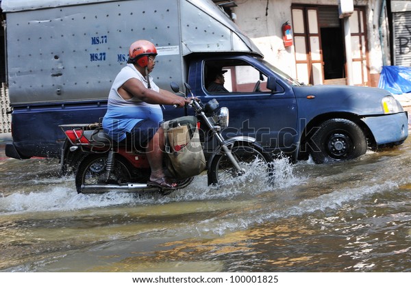 BANGKOK -\
NOVEMBER 1: An unidentified motorbike rider navigates a flooded\
street in Chinatown after the heaviest monsoon rains in over 50\
years on November 1, 2011 Bangkok,\
Thailand.