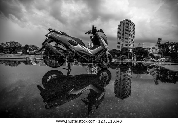 Bangkok: October 5, 2018, at Benjakitti Park,\
near the Queen Sirikit Convention Center, motorcycles and cars\
parked in the rain,\
Thailand