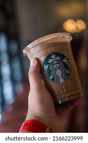 Bangkok, Samut Prakan - June 11, 2022 : Holding a cup of Almondmilk White Chocolate Affogato Frappuccino from Starbucks coffee. Starbucks is the world's largest coffeehouse and is highly popular