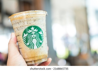 Bangkok, Samut Prakan - June 18, 2022 : Holding a cup of Almondmilk White Chocolate Affogato Frappuccino from Starbucks coffee. Starbucks is the world's largest coffeehouse and is highly popular