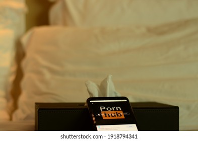 Bangkok \ Thailand - 02 16 2021: Bored internet user browsing pornhub on smartphone alone in his hotel room.