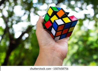 Bangkok, Thailand, 14 September 2019, Woman's Hand Holding Rubik's Cube And Playing With It, In Bokeh Green Background, Rubik's Cube Invented By A Hungarian Architect Erno Rubik In 1974, Game Concept