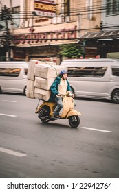 Bangkok, Thailand - 15/11/2018: Vespa courier carrying overloaded boxes through traffic. Motorbike transportation in Bangkok