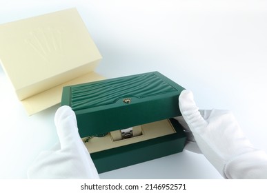 Bangkok, Thailand, 18 April 2022, the green leather box of Rolex wristwatch is on white table and is opened by hands with white glove in authorized dealer Rolex shop