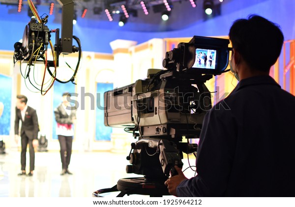 Bangkok, THAILAND - 24 February 2021 : A\
cameraman\'s back view with a high quality television camera in\
television production.