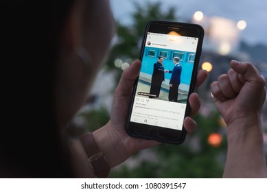 BANGKOK, THAILAND- 30th April 2018 :Hands of woman with joy watching video clip of Kim Jong-un, north korean leader shaking hands with Moon Jae-in, president of south korea via Instagram application - Shutterstock ID 1080391547