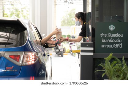 Bangkok Thailand 5 August 2020 - staff with protective mask serving starbucks coffee to customer at drive thru counter during coronavirus outbreak Social distancing , Bangkok Thailand