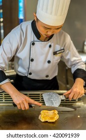 Bangkok, Thailand - 7 May 2016 - Female Chef Slices Delicious Chicken Teriyaki To Serve The Customer In A Teppanyaki Kitchen.