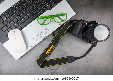 Bangkok, Thailand - April, 04, 2020 :  Green Frame Glasses, Notebook Computer And Dslr Nikon D5300 Isolated On The Table, Stone Pattern.