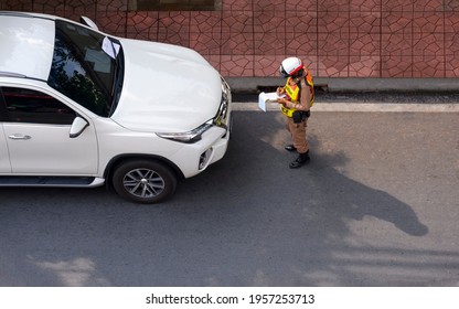 Bangkok, Thailand - April 12,2021: Top View Of Asian Policeman Writing Traffic Ticket For White Car That Parked In Prohibited Parking Space On The Road In The City