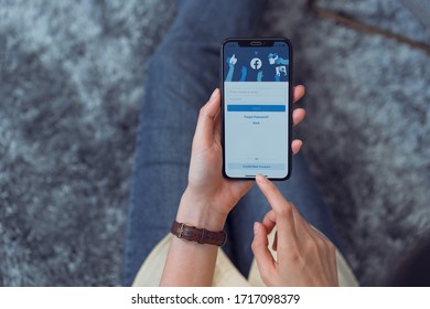 BANGKOK, THAILAND - April 29, 2020 : Hand Is Holding Smartphone And The Facebook Screen On Apple IPhone, Social Media Are Using For Information Sharing And Networking.