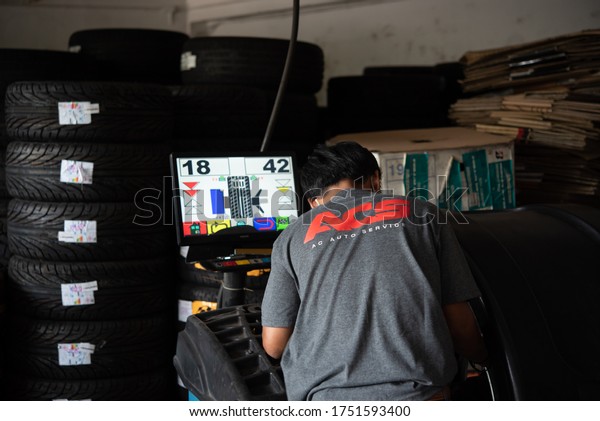 Bangkok, Thailand - April 4, 2020 : Unidentified car\
mechanic or serviceman wheel alignment and tire balance checking\
car wheel for fix and repair suspension problem at car garage or\
repair shop
