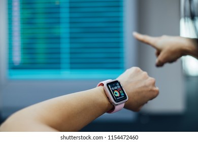 Bangkok, Thailand - Aug 7,2018: Young Woman/traveler Girl In International Airport Looking Apple Watch At The Flight Information Board, Checking Her Flight