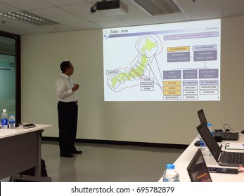 BANGKOK, THAILAND - AUGUST 10, 2017: An Asian Man Gives A PowerPoint Presentation To Other People In The Meeting Room.