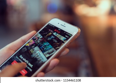 Bangkok, Thailand - August 13, 2018 : women use Netflix app on smart phone screen. Netflix is an international leading subscription service for watching TV episodes and movies.