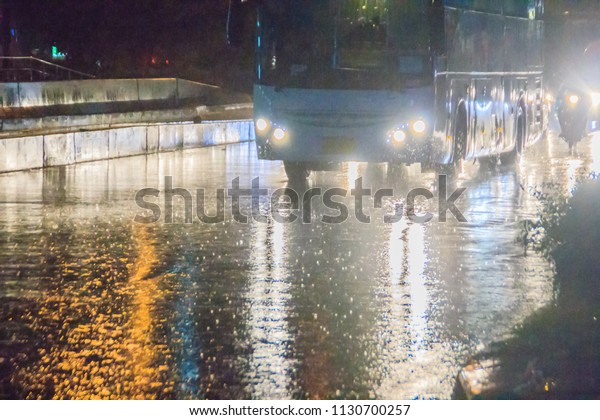 Bangkok, Thailand - August 17, 2017: Driving car\
through the heavy rain in the evening. Traffic under heavy rain\
with hail in dangerous situation with low visibility, slippery and\
splashing water.
