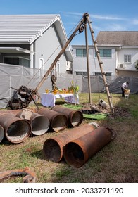 BANGKOK, THAILAND - AUGUST 19, 2021 : Tripod Rig And Drilling Bucket Behind Temporary Castings Prepared For Dry Process Bored Pile At The Site Of New House Construction