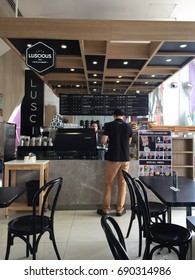 BANGKOK, THAILAND - AUGUST 4, 2017: An Unidentified Asian Tall Man Wearing Black Polo Shirt And Brown Trousers Buys Coffee From A Coffee Shop Decorated With Black Furniture.