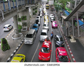 Bangkok, Thailand - December 10, 2016: Cars in traffic jams on long street in centre of Bangkok. In the foreground colorful Bangkok taxi (taxi-meter).
