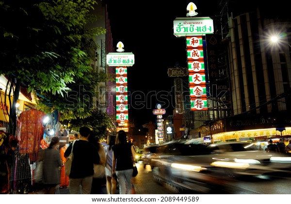Bangkok, Thailand -\
December 11, 2021: Colorful signs and the light trails from traffic\
 moving on the night of Yaowarat Road, Bangkok street market.      \
                      